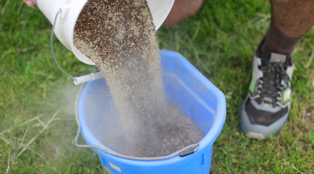Wildflower seed being poured into a blue bucket