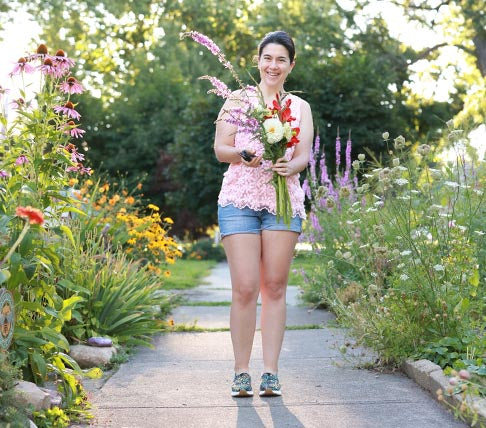 woman holding a bouquet of flowers standing on a sidewalk