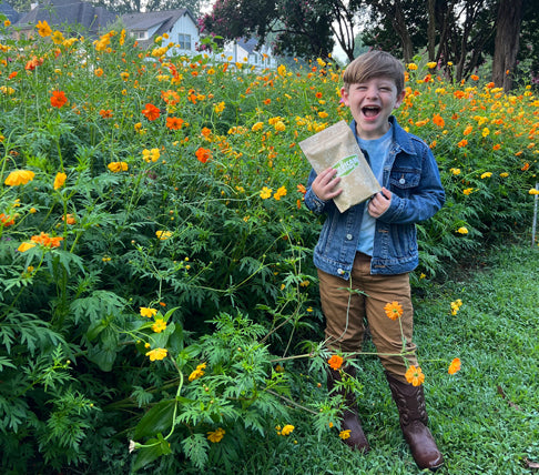 Young boy grinning in a field of wildflowers